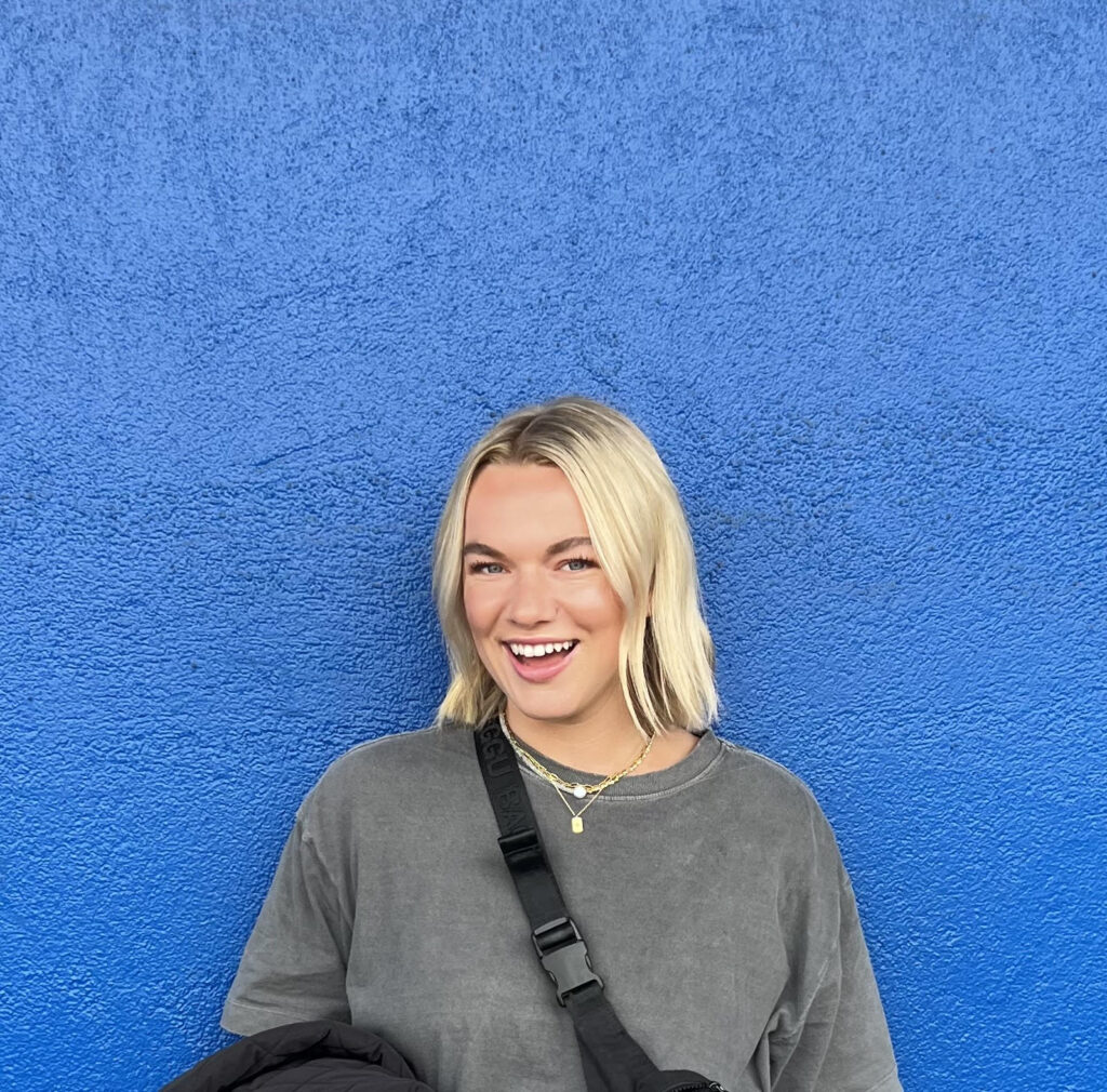 Photo of Community Mentor, Kitty. She is standing in front of a blue wall.